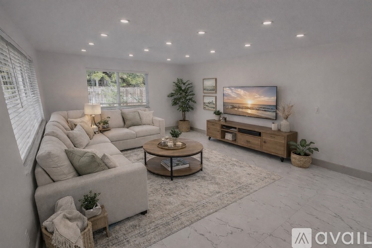 A modern living room with a large couch, a coffee table, and a flat-screen TV.