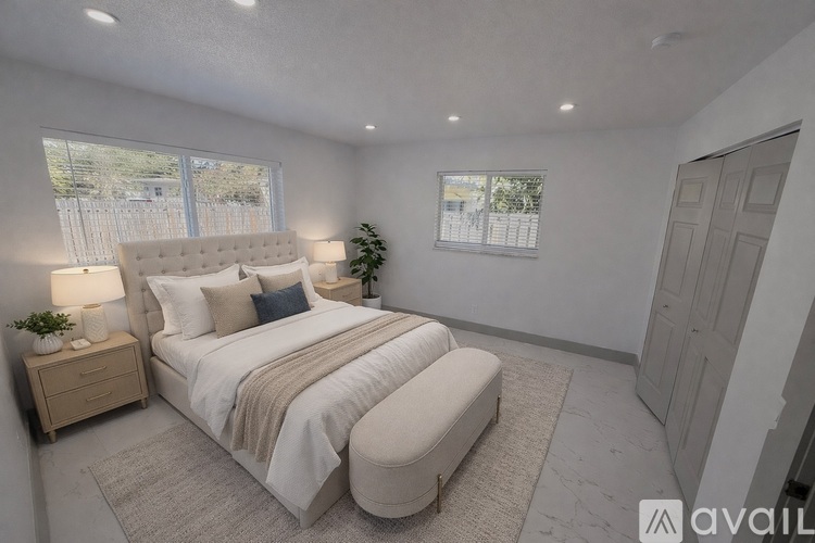 A bedroom with a large bed, a nightstand, and a window.