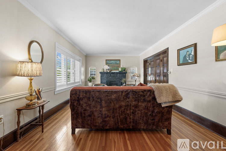 A bedroom with a bed, a table with a lamp, and a mirror on the wall.