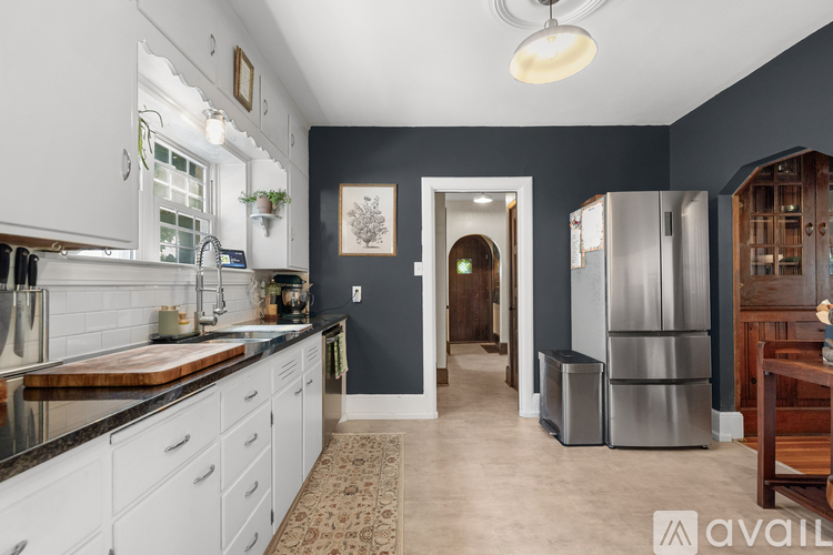 A kitchen with white cabinets and a wooden cutting board.