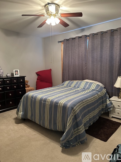A bedroom with a bed, dresser, and ceiling fan.