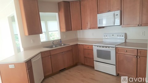A kitchen with brown cabinets and white appliances.