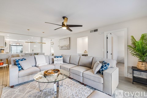 A living room with a grey sofa and a glass coffee table.