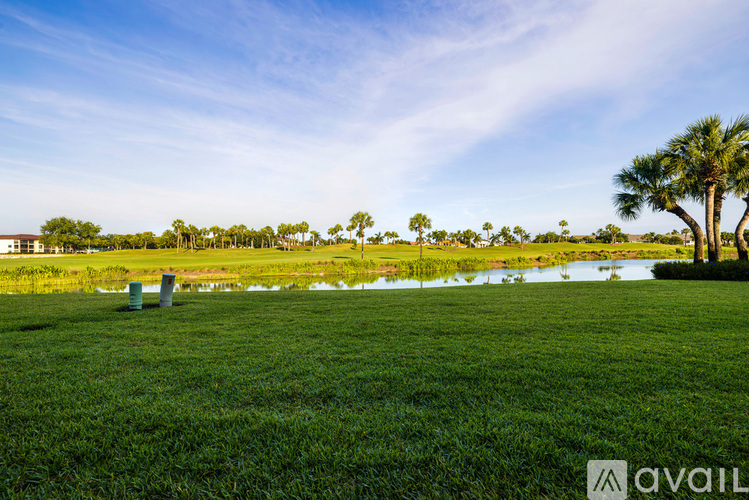 A grassy field with a body of water and trees in the distance.