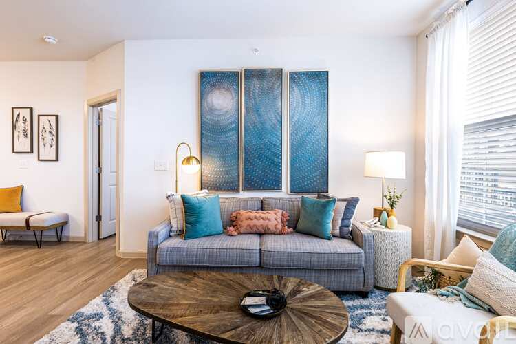 A living room with a grey couch, a coffee table, and a large abstract painting on the wall.