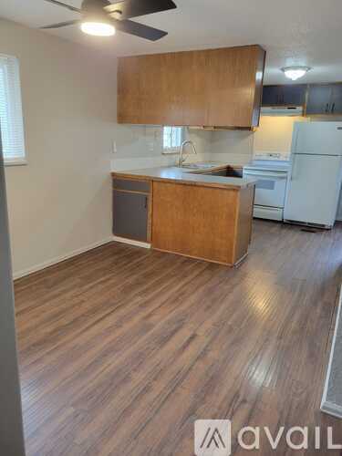 A kitchen with wooden floors and a white refrigerator.