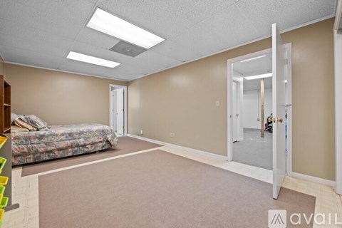 A bedroom with a bed, carpet, and a mirror.