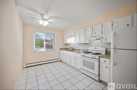 A kitchen with white appliances and cabinets is available for rent.