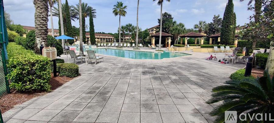 A pool surrounded by palm trees and a fence.