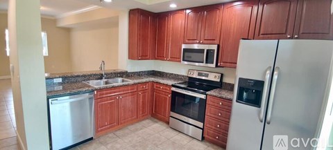 A kitchen with wooden cabinets and a stainless steel refrigerator.