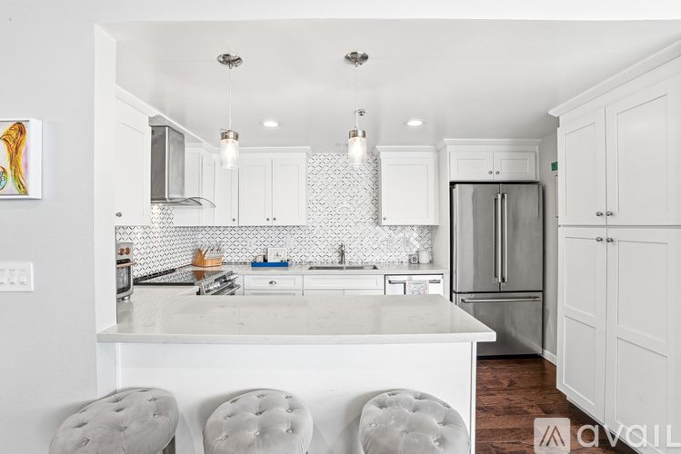 A kitchen with white cabinets and a white island.