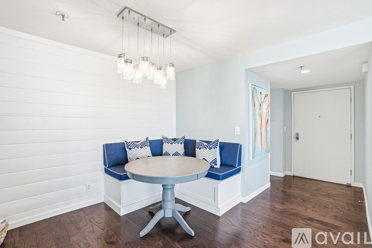 A dining room with a round table and a bench with cushions.