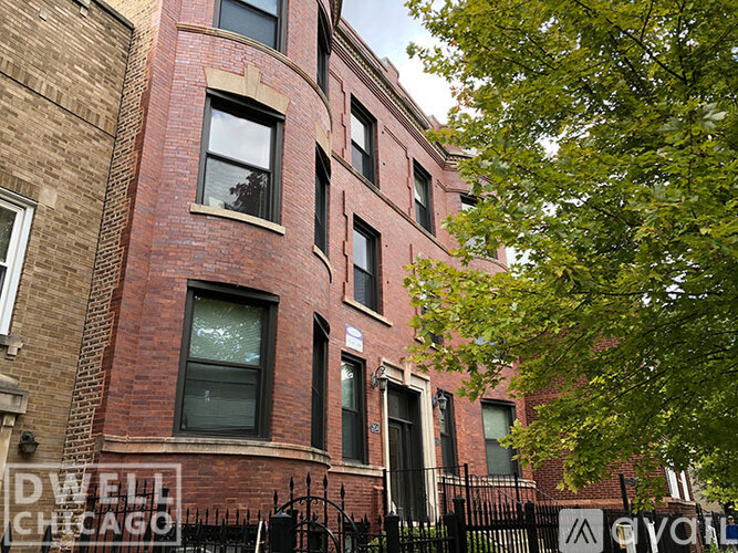 A red brick building with a black fence in front.