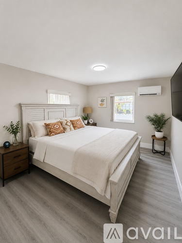 A bedroom with a large bed, wooden nightstand, and a plant on the side table.