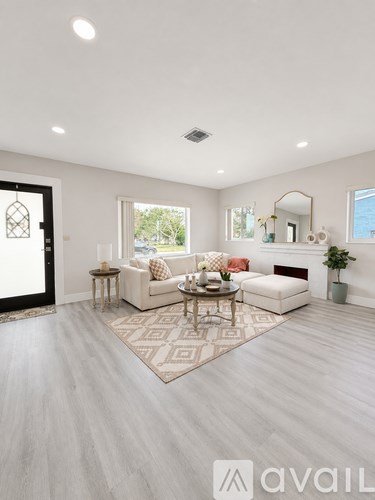 A living room with a white sofa set and a rug.