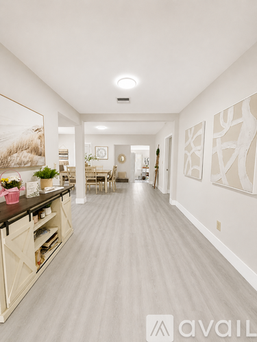 A long, narrow hallway with a kitchen area on the left and a dining area in the distance.