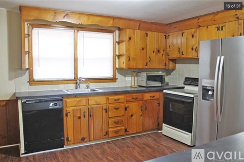 A kitchen with wooden cabinets and a black dishwasher.