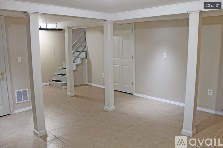 A spacious room with a staircase and a door.