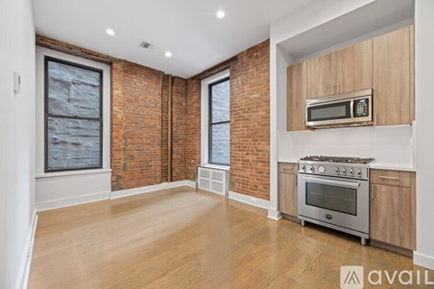 A kitchen with a brick wall and wooden floors.
