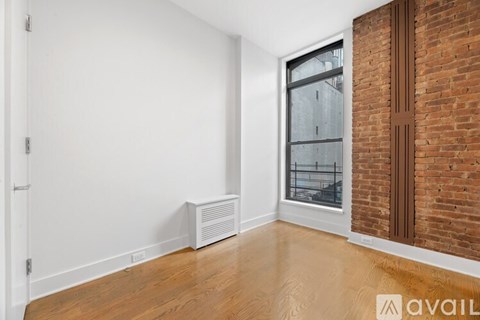 A room with a window and a brick wall.