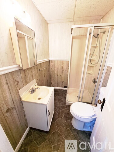 A small white bathroom with a toilet, sink, and shower.