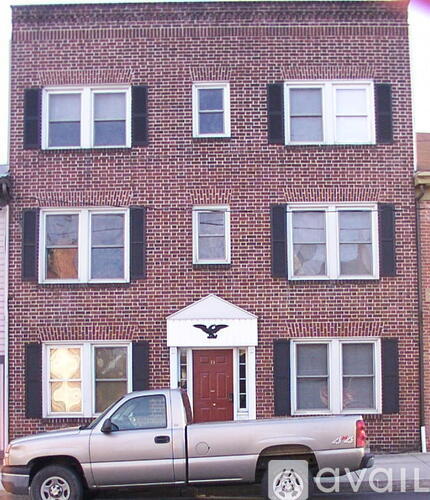 A silver truck is parked in front of a red brick building.