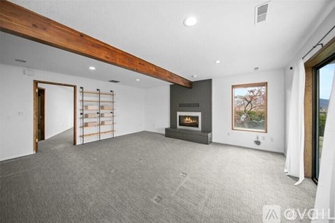 A spacious living room with a fireplace and a painting on the wall.