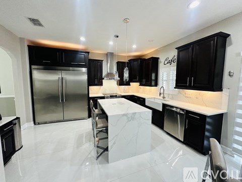 A modern kitchen with black cabinets and stainless steel appliances.