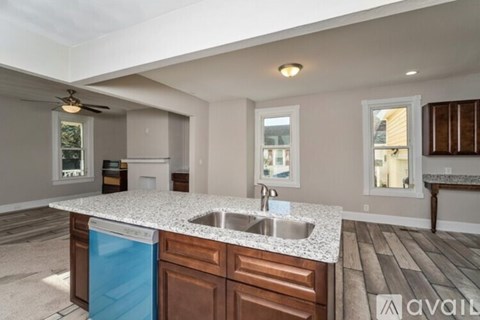 A kitchen with a blue trash can and a white counter top.