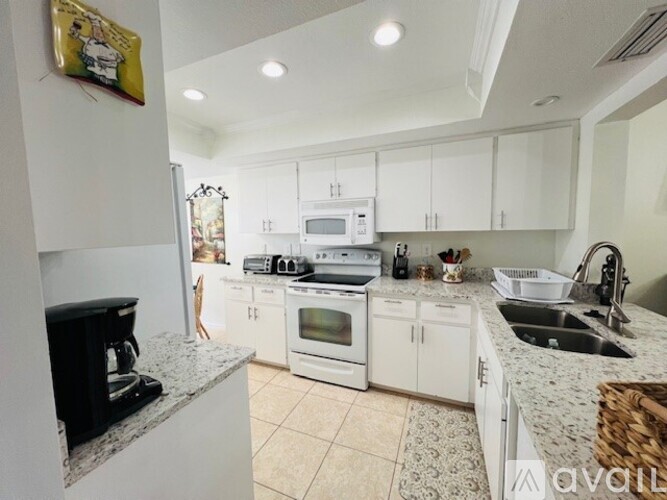 A kitchen with white cabinets and a black countertop.