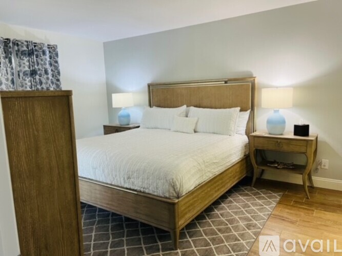 A bedroom with a large bed and a wooden nightstand.