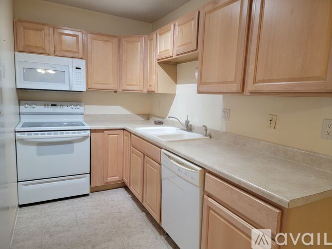 A kitchen with wooden cabinets and white appliances.