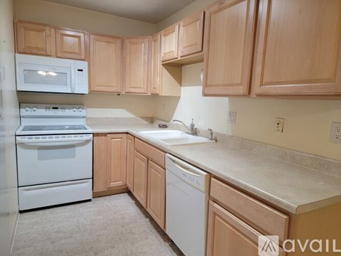 A kitchen with wooden cabinets and white appliances.
