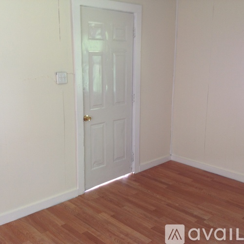 A white door is in a room with wooden flooring.
