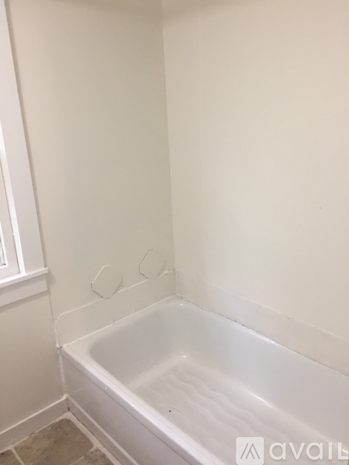 A white bathroom with a tub and a white wall.