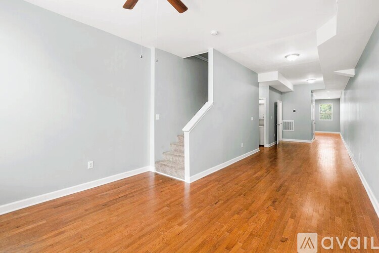 A spacious room with wooden floors and a staircase leading to another room.
