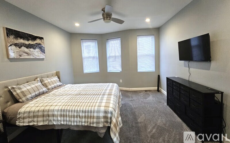 A bedroom with a bed, dresser, and television.