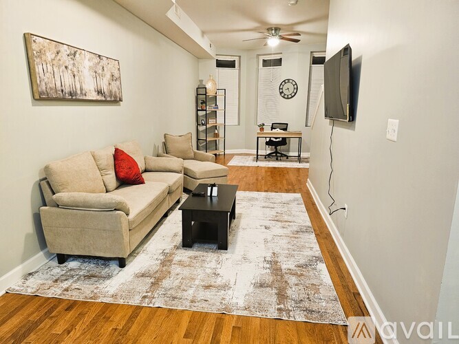 A living room with a beige couch and a rug.