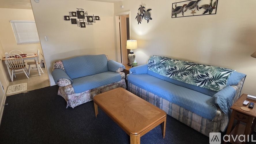 A living room with a couch, a bed, and a wooden table.