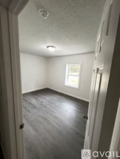 A room with a window and wooden flooring.