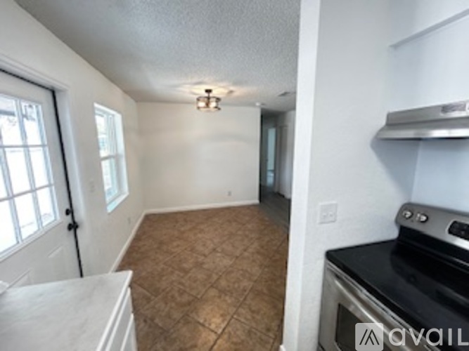 A kitchen with a stove top oven and a tile floor.