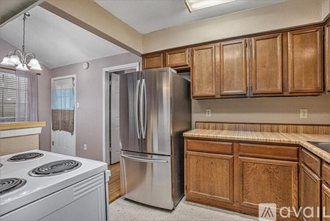 A kitchen with wooden cabinets and a stainless steel refrigerator.