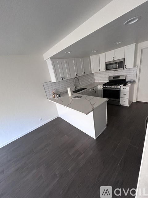 A kitchen with a white island and black countertops.