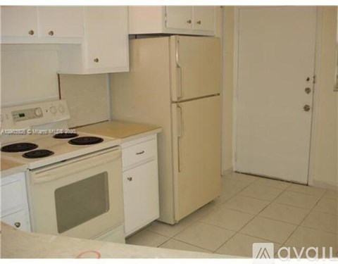 A white kitchen with a fridge, oven and stove.