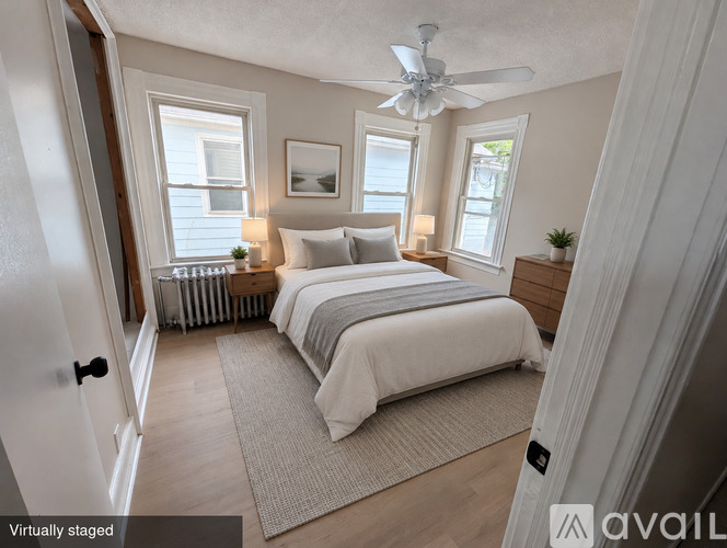A bedroom with a bed, two lamps, a ceiling fan, and a rug.