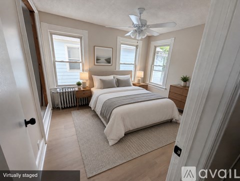A bedroom with a bed, two lamps, a ceiling fan, and a rug.