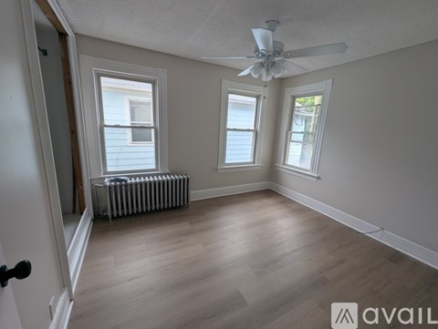A room with a ceiling fan and two windows.