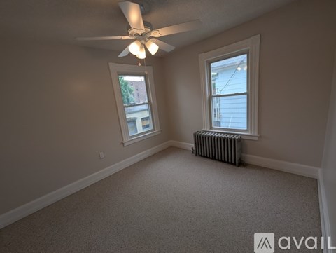 A room with a ceiling fan and two windows.