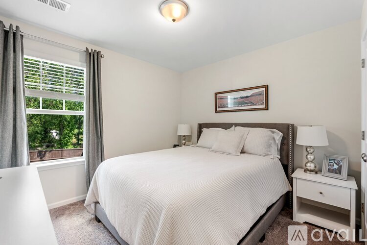 A bedroom with a large bed and a window with blinds.