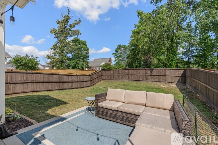 A backyard with a patio, a couch, and a pool.